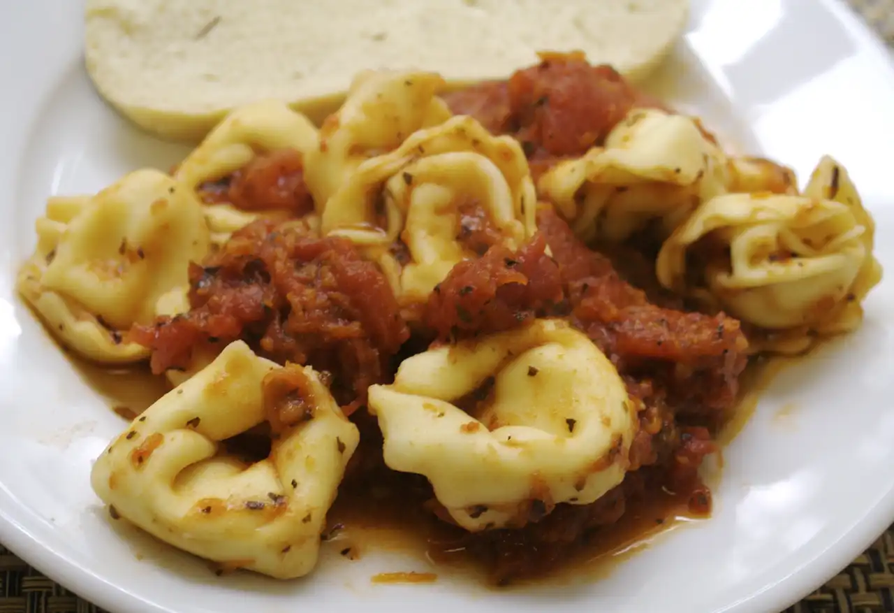 Cheese tortellini boiling in a large pot of water on a home stove