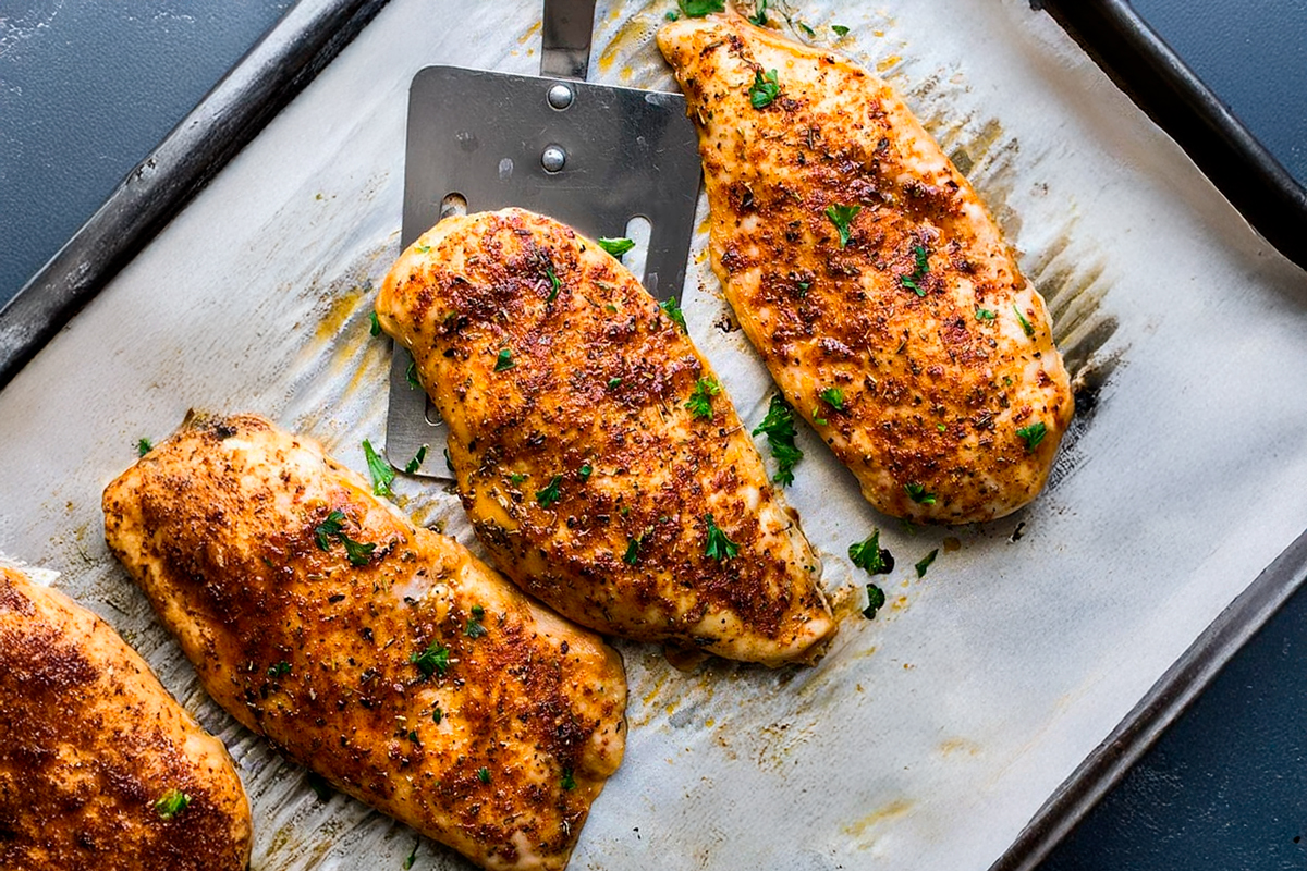 Chicken breasts on a cutting board seasoned with herbs and spices, ready to cook