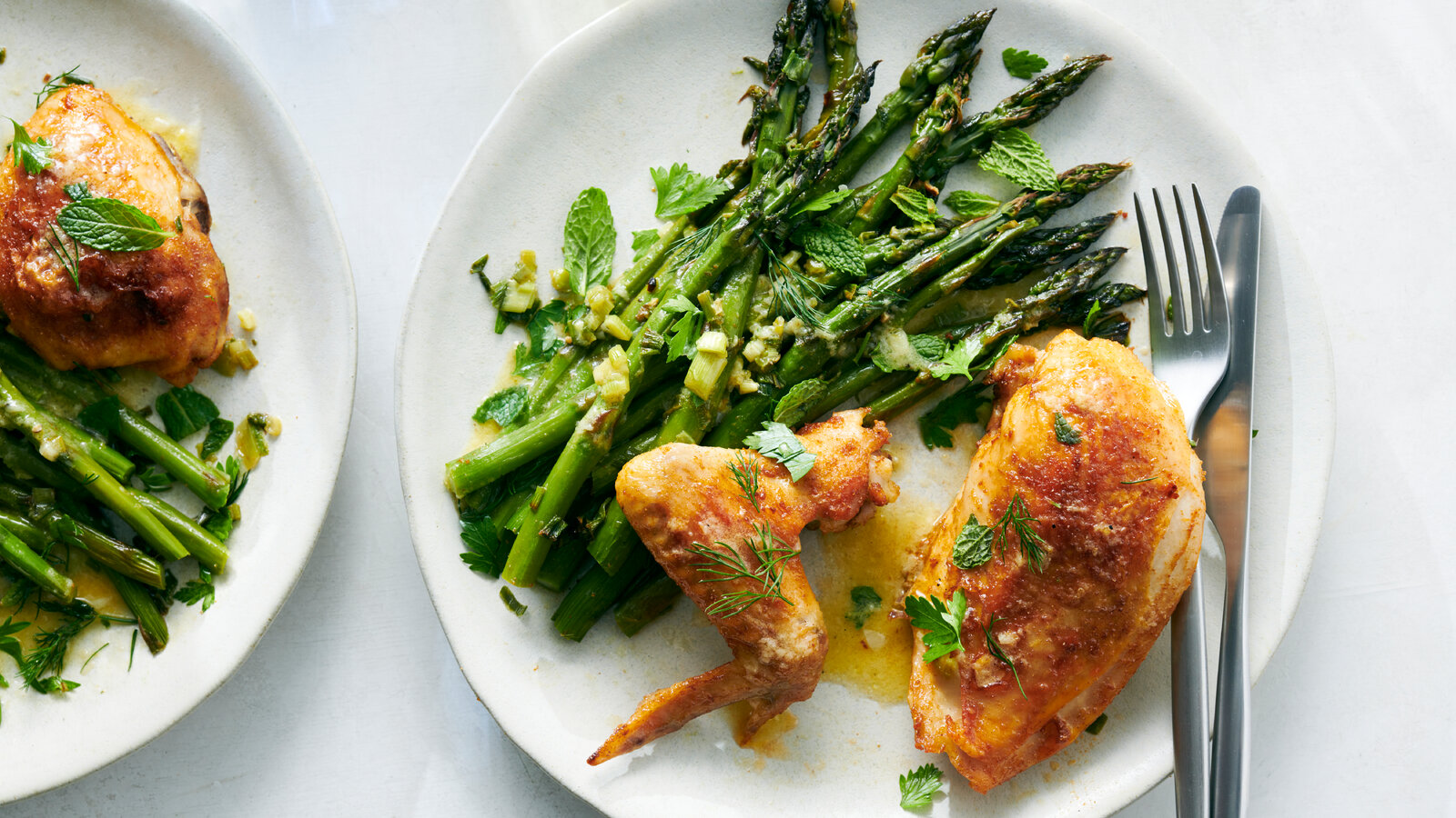Chicken cutlets, fresh asparagus, lemon, garlic, cream, and Parmesan arranged on a clean kitchen counter with small bowls of salt and pepper