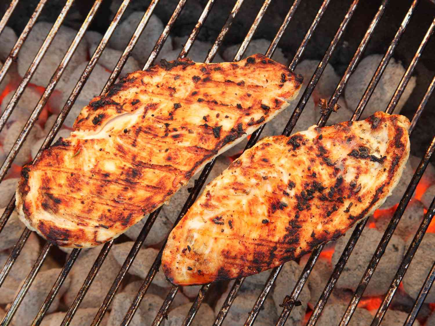 Chicken cutlets on a cutting board being sprinkled with salt, pepper, and paprika