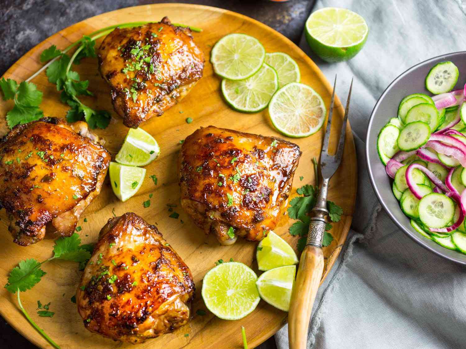 Chicken thighs and drumsticks evenly coated in a reddish-brown dry rub on a sheet pan lined with parchment on a kitchen counter