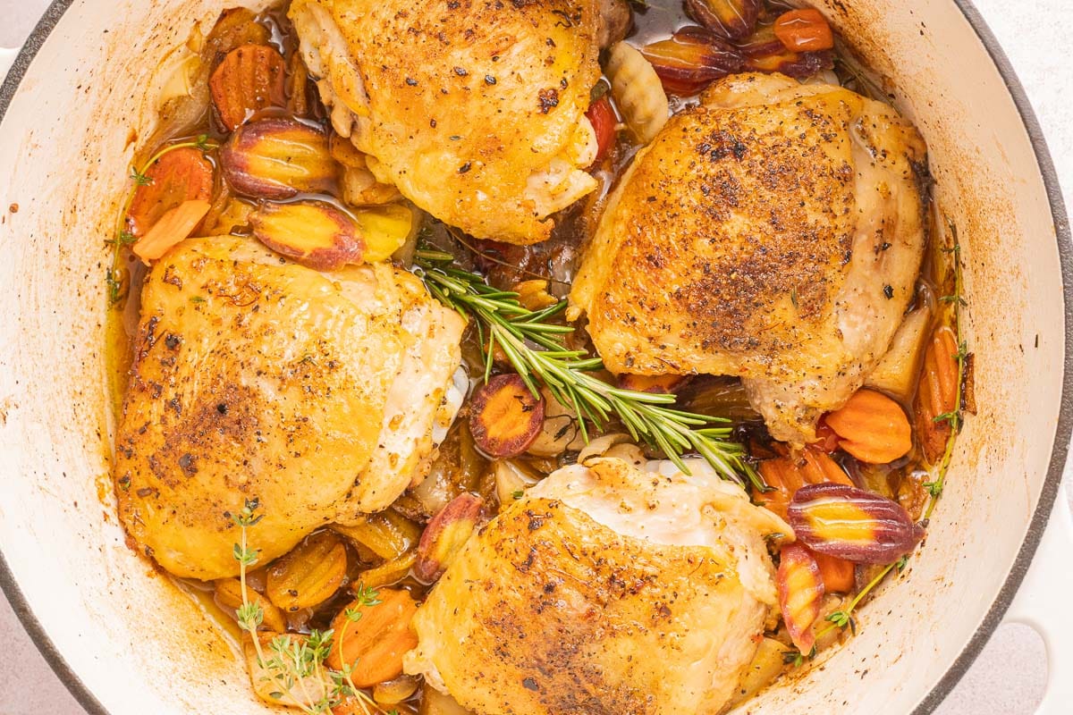 Chicken thighs searing skin-side down in a Dutch oven as the skin turns golden and rendered fat collects in the pot