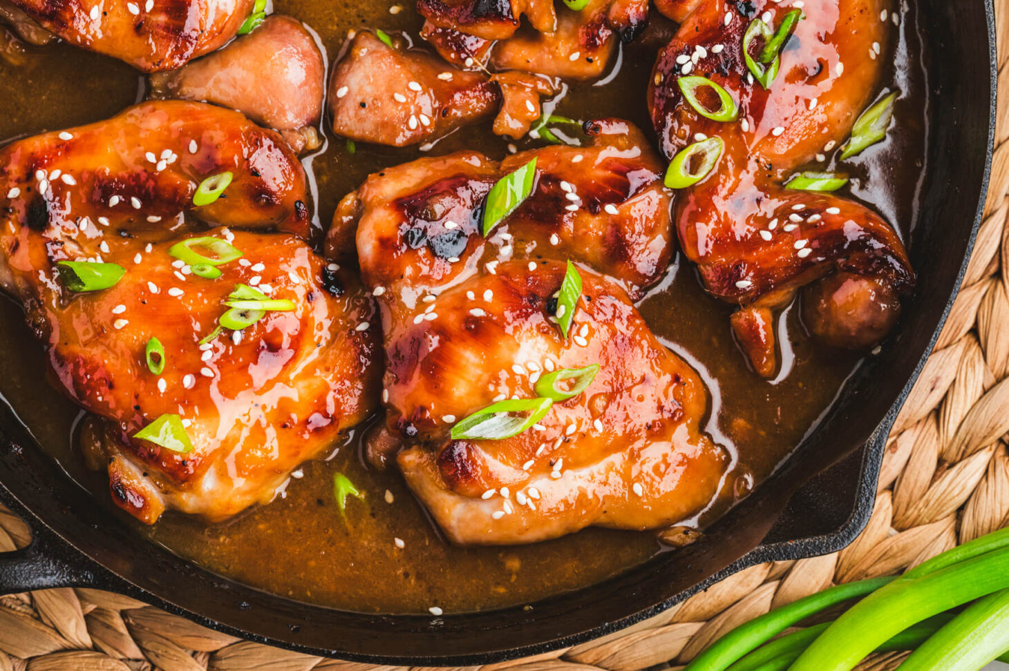 Chicken thighs, soy sauce, honey, garlic, ginger, limes, and scallions arranged on a clean kitchen counter with measuring spoons