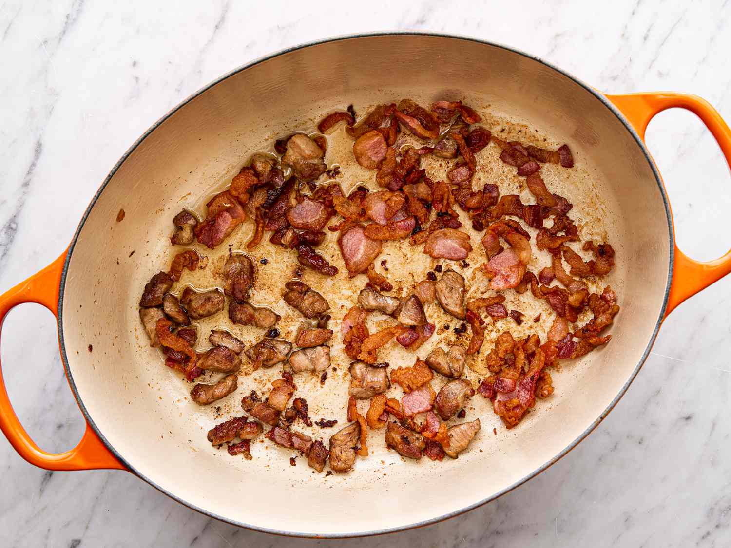 Chopped bacon and raw chorizo ready to cook in a Dutch oven, with diced onion on a cutting board nearby