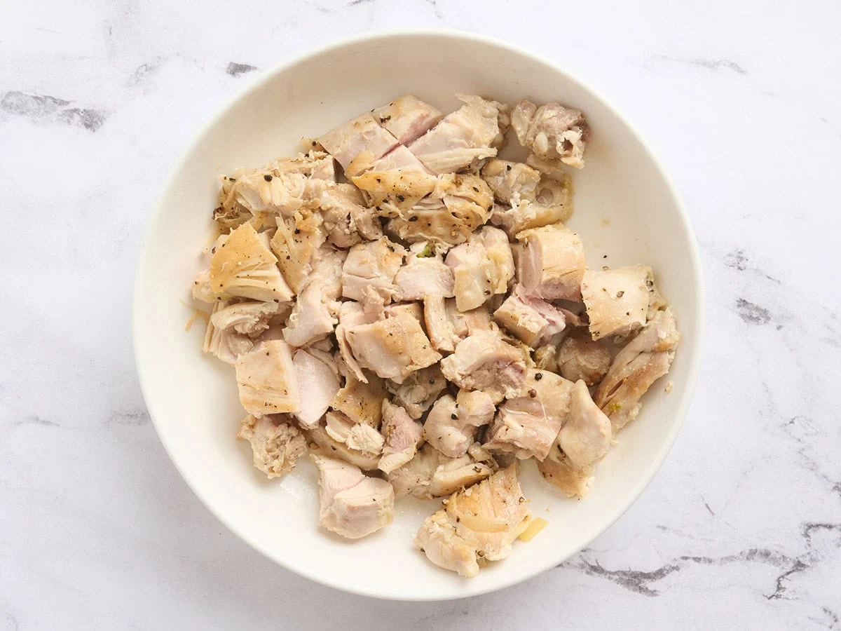 Chopped cooked chicken piled in a large mixing bowl on a kitchen counter