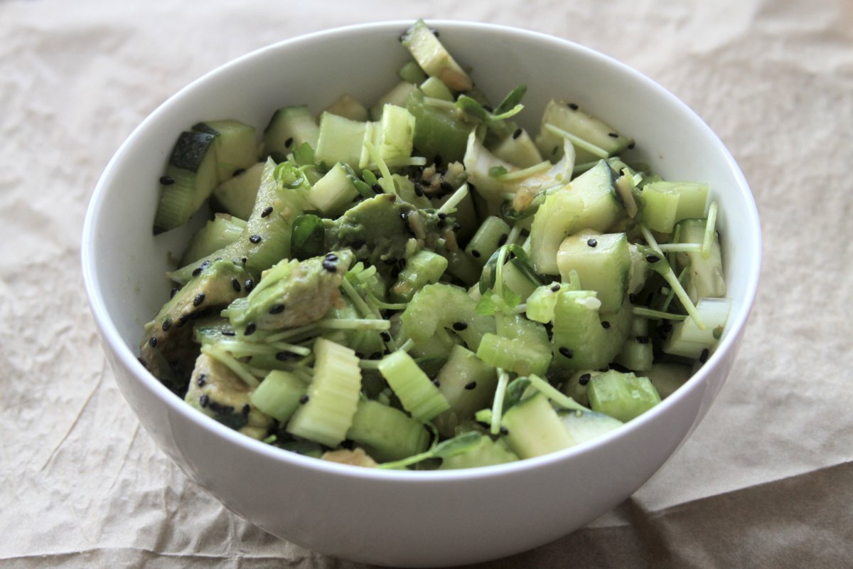 Chopped cucumber and celery pieces on a wooden cutting board in a home kitchen