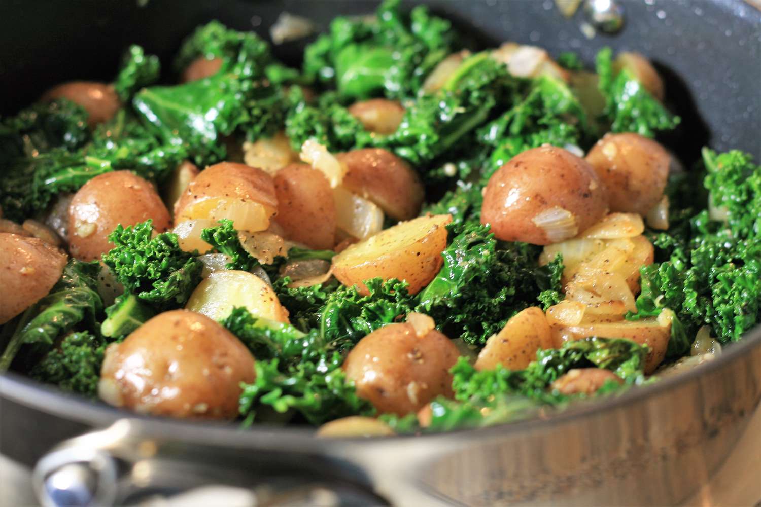 Chopped kale, sliced Yukon Gold potatoes, diced onion, and minced garlic arranged in small bowls, ready for soup prep