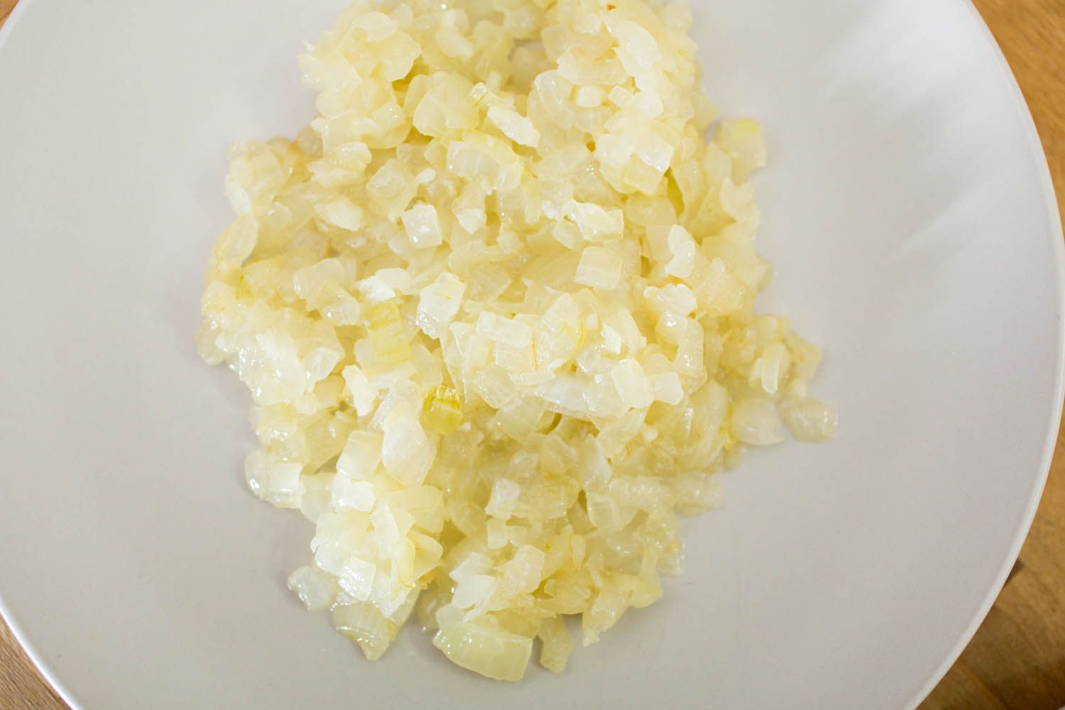 Chopped onion and minced garlic on a cutting board with small bowls of cumin, smoked paprika, oregano, and salt nearby