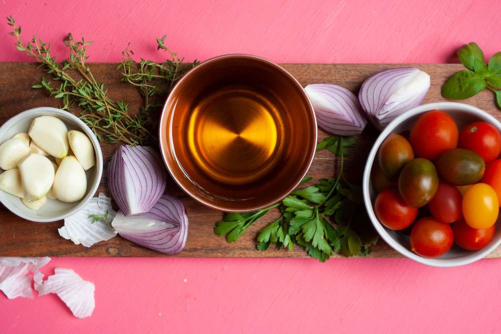 Chopped onion, chopped tomatoes, minced garlic, and grated ginger prepped in small bowls on a bright kitchen counter