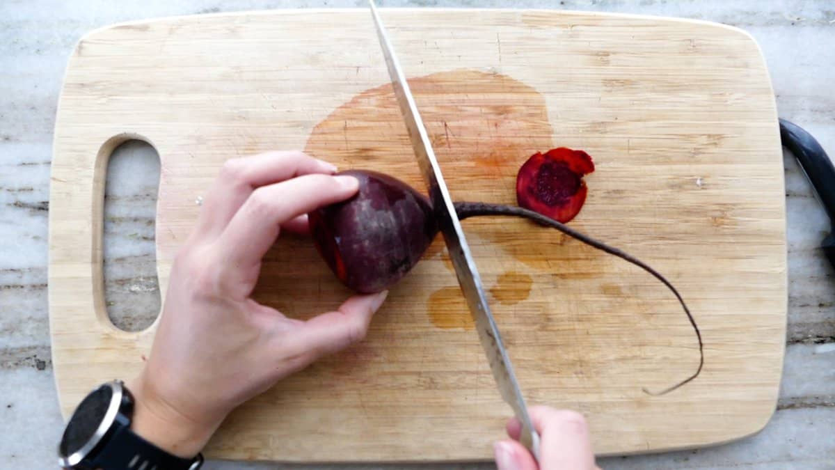 Chopped raw beets in 1-inch pieces on a cutting board with a chef’s knife beside them