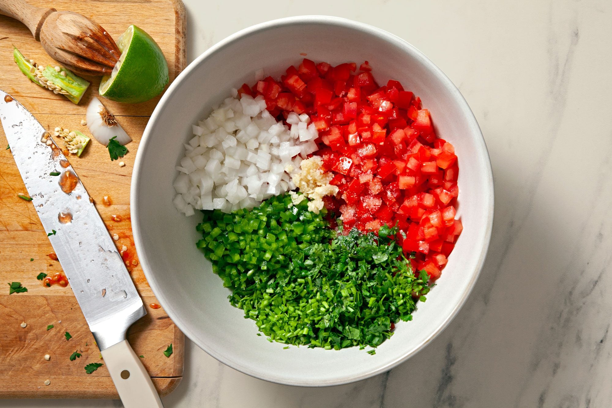Chopped ripe tomatoes, minced garlic, chopped cilantro, and small bowls of spices arranged on a cutting board