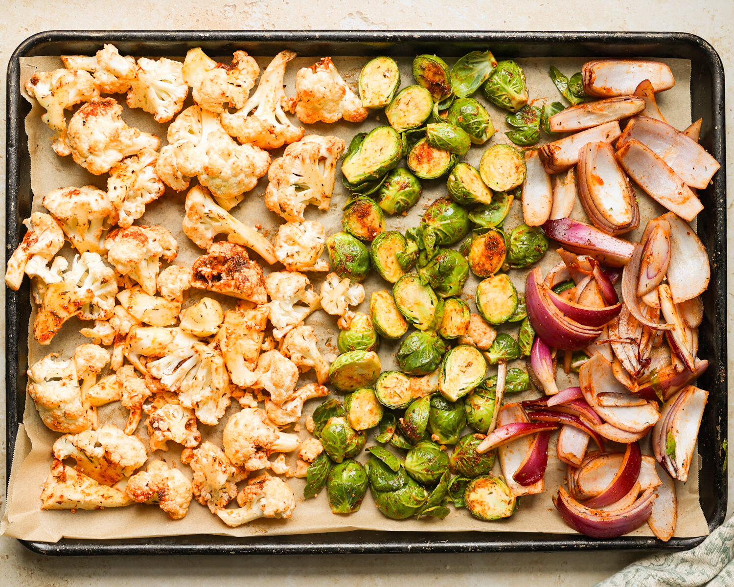 Chopped vegetables spaced in a single layer on a rimmed sheet pan before roasting