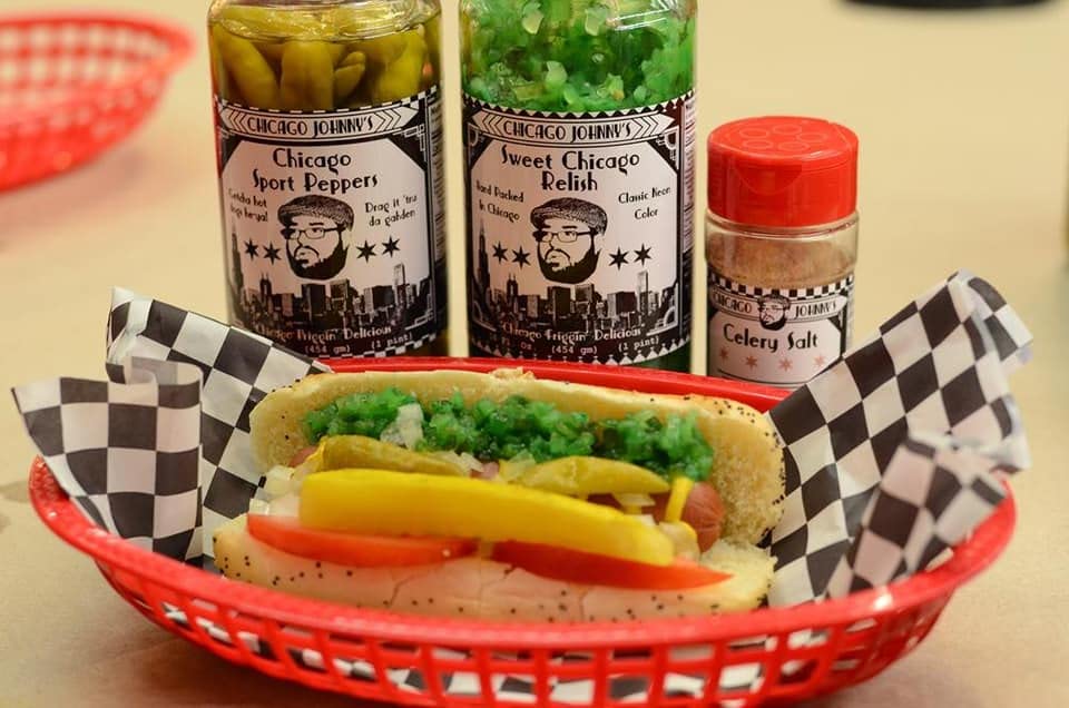 Close-up of celery salt, sport peppers, and bright green relish in small bowls on a kitchen counter with warm, natural light