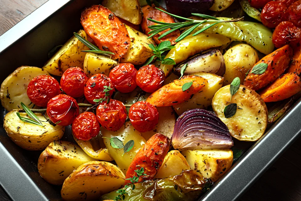 Close-up photo of roasted vegetables on a sheet pan showing caramelized edges and glistening olive oil