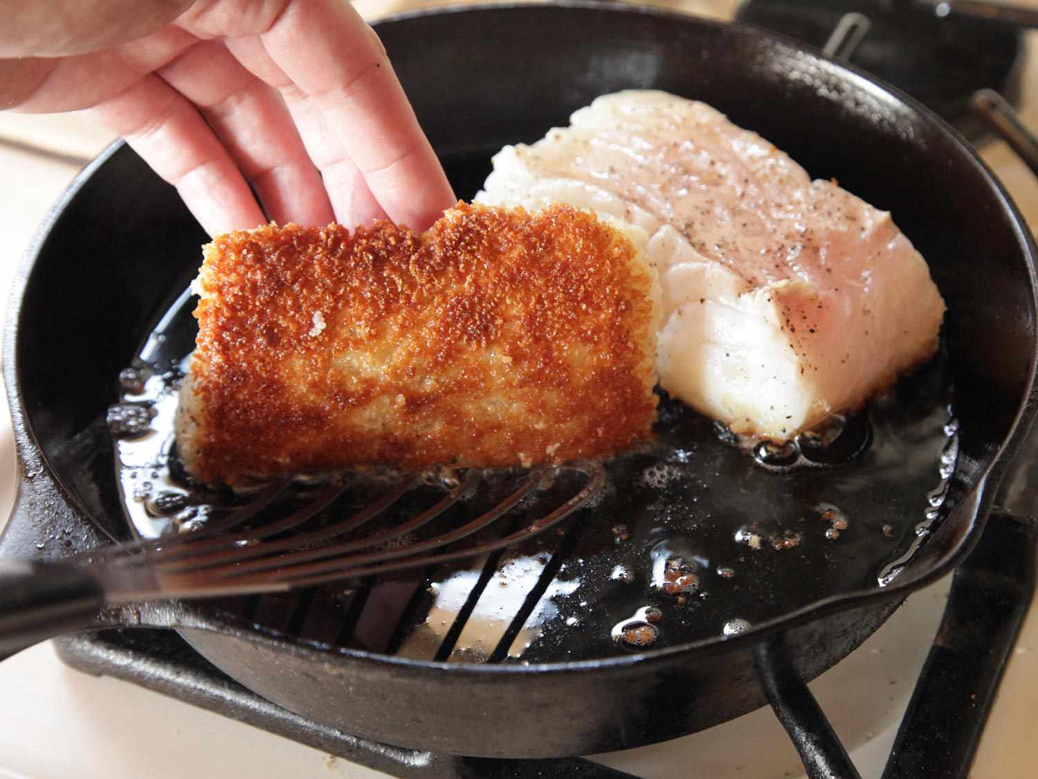 Cod fillets on a sheet pan beside a shallow bowl of seasoned flour, lemon, and spices on a bright kitchen counter with even natural light