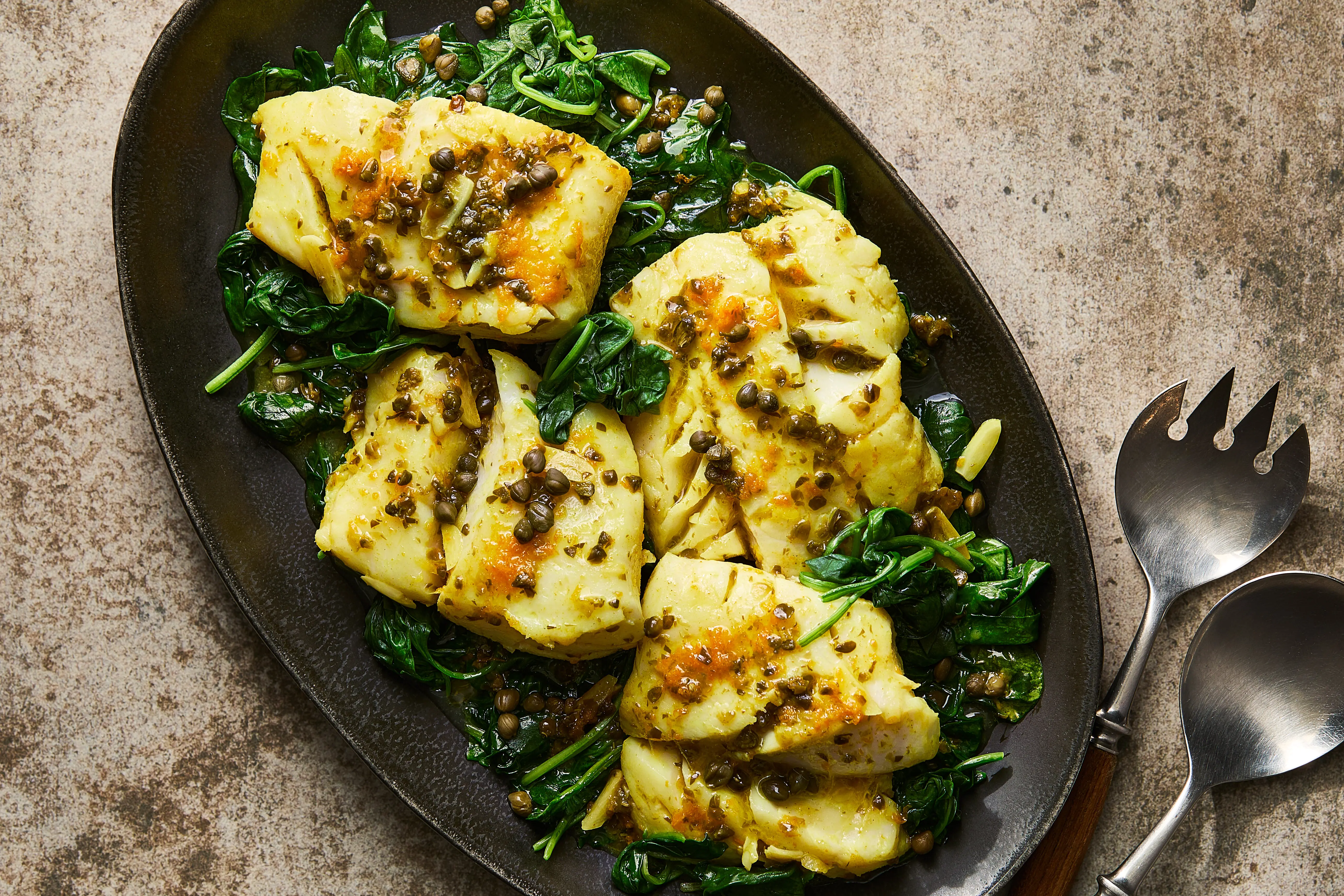 Cod fillets seasoned with paprika and spices on a cutting board with a small bowl of mixed seasoning nearby on a kitchen counter