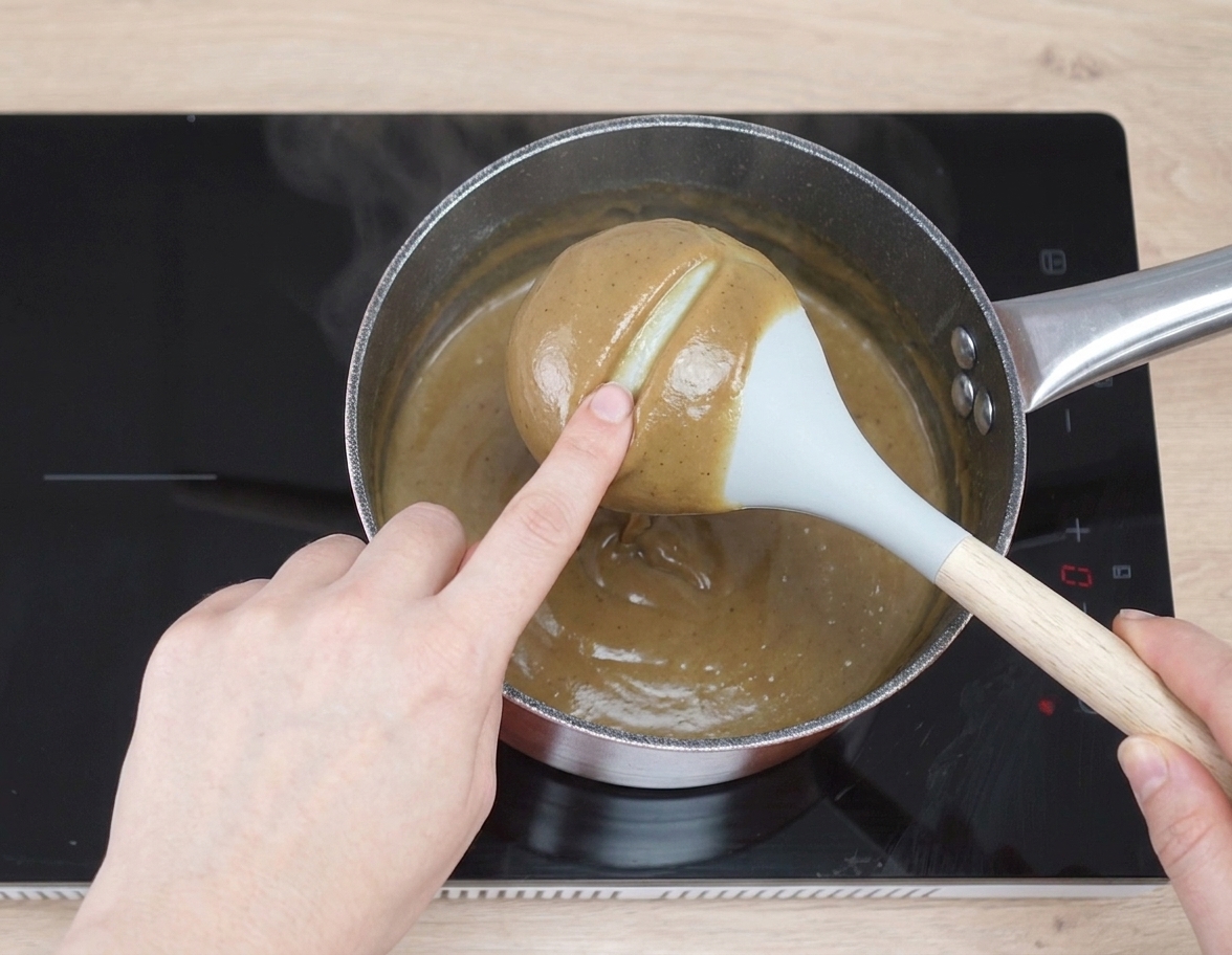Coffee custard thickened in a saucepan, coating the back of a spoon with a clean line drawn through it