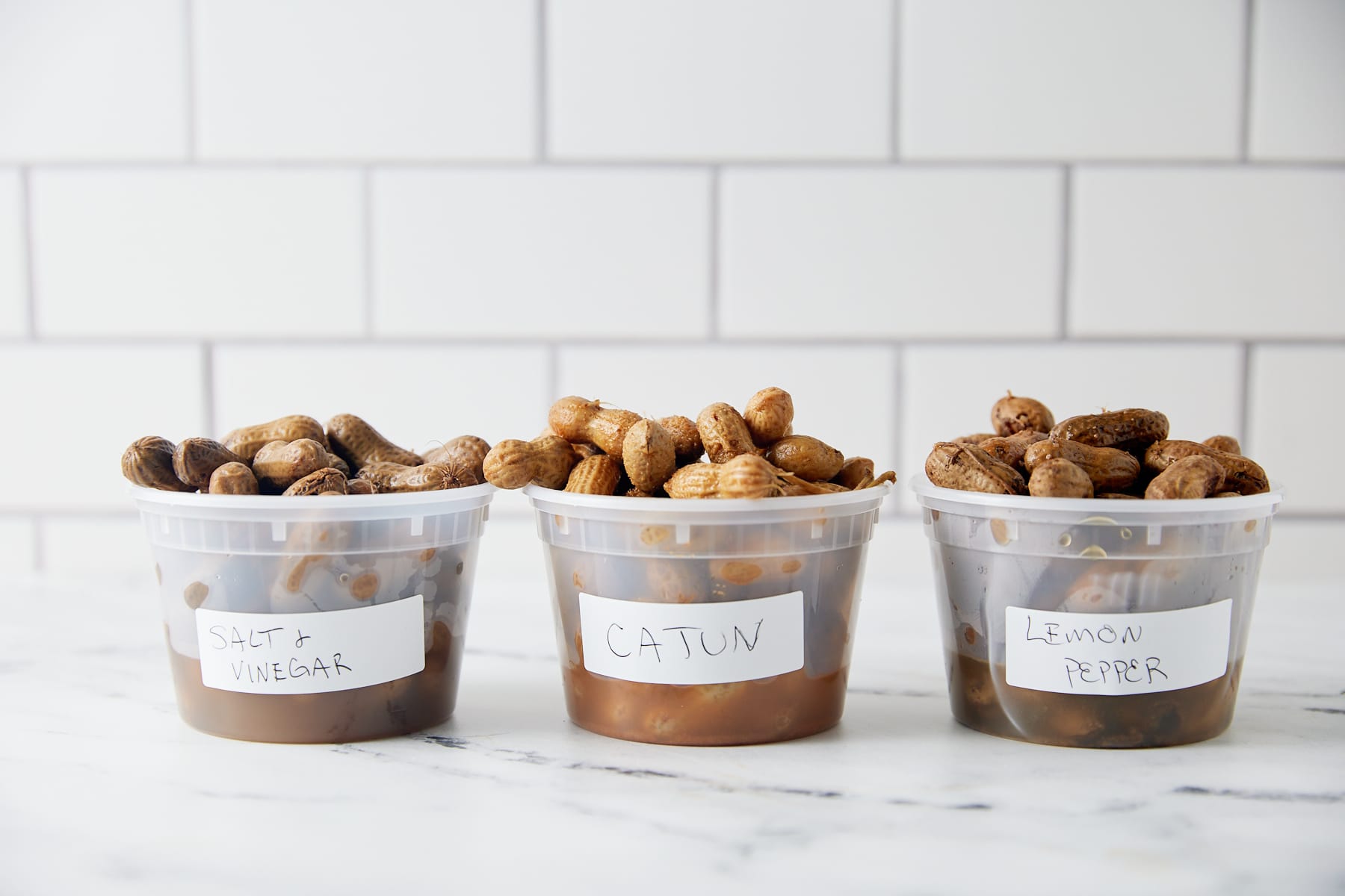 Cooked peanuts in the shell submerged in brine inside a clear airtight container in a refrigerator