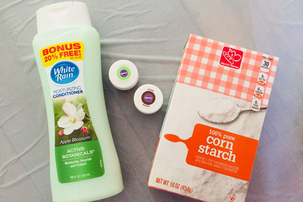 Cornstarch in a small bowl and a bottle of white hair conditioner arranged on a clean kitchen counter, top down view in natural light