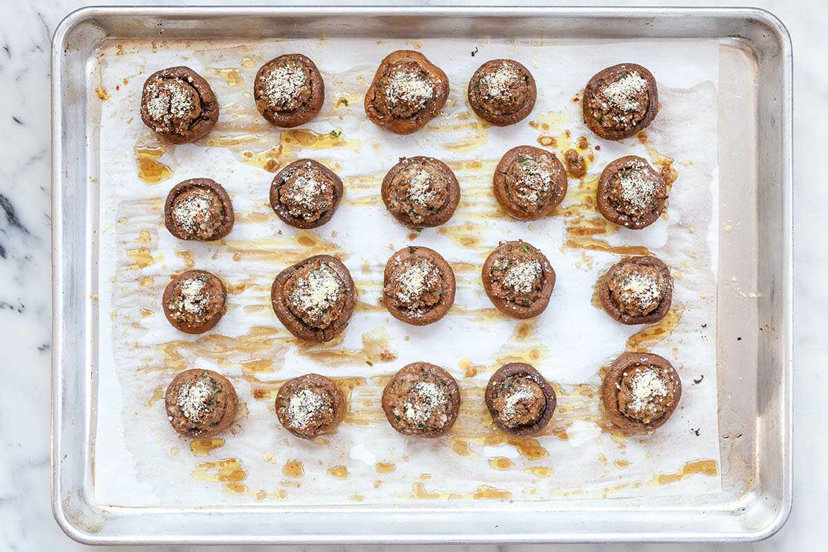 Crab stuffed mushrooms arranged on a parchment-lined baking sheet ready to go into the oven on a bright kitchen counter
