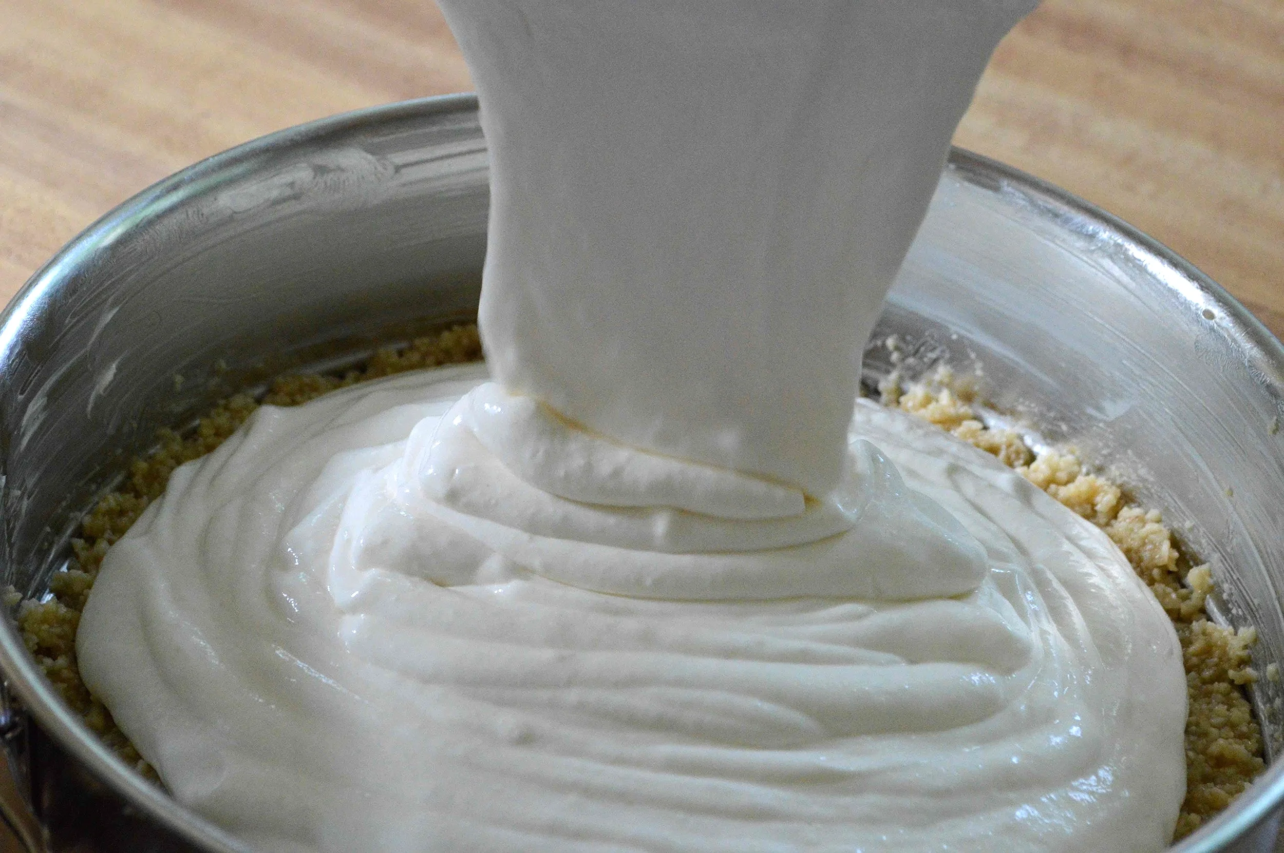 Cream cheese, sugar, eggs, sour cream, vanilla, and flour measured out on a clean kitchen counter next to mixing bowls