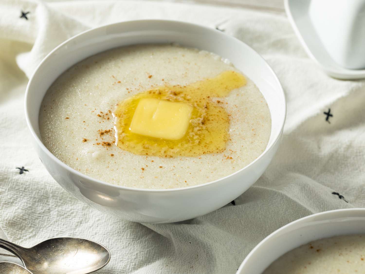 Cream of Wheat farina measured into a small bowl on a warm-lit kitchen counter next to a whisk and saucepan