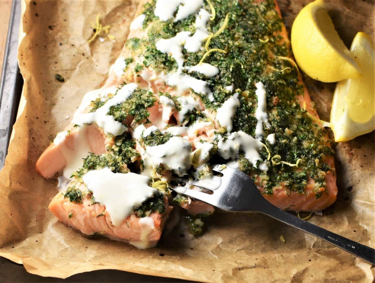 Crisp-seared salmon fillets with lemon slices and chopped herbs in a glossy pan sauce on a warm kitchen counter with soft natural light