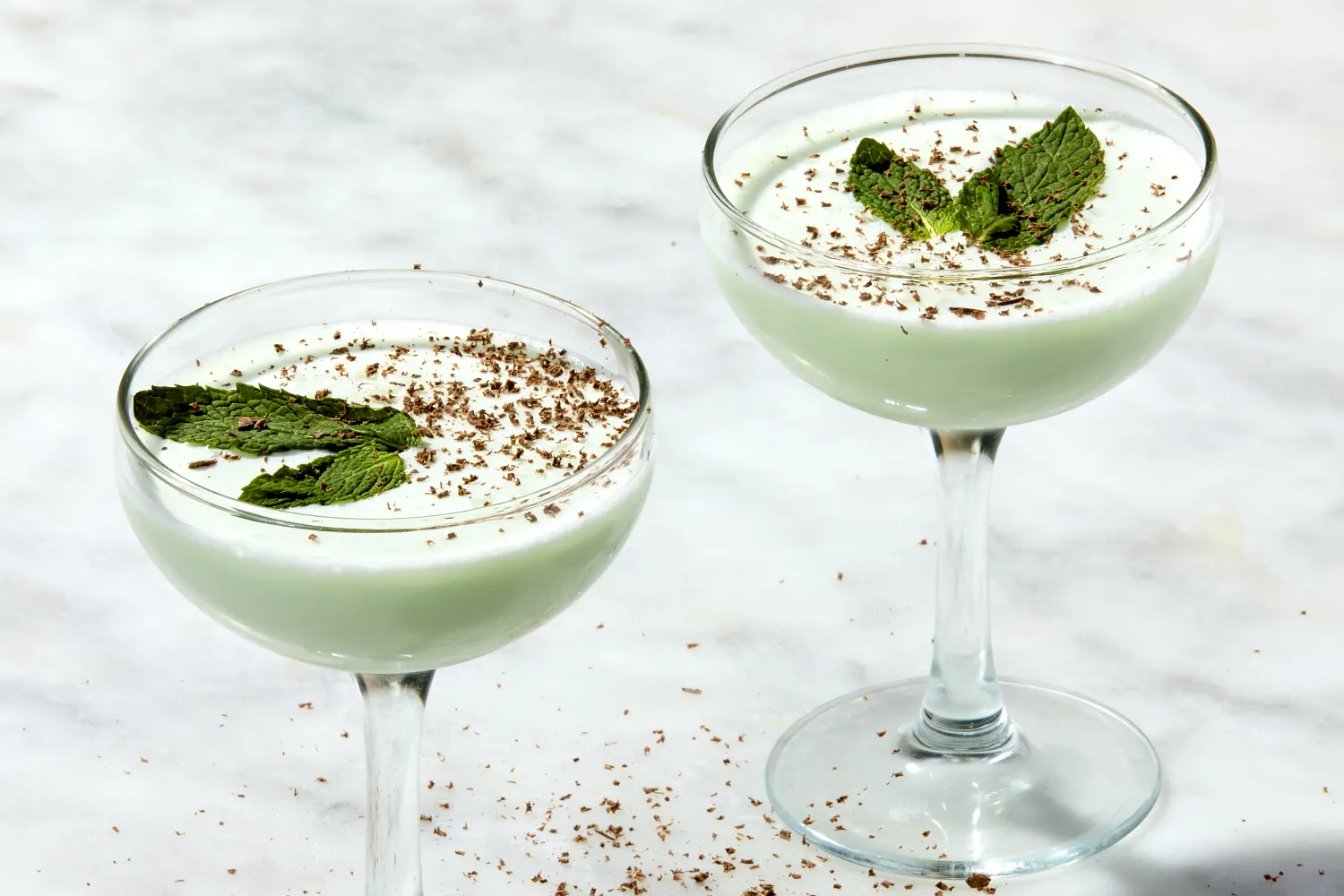 Crème de menthe, crème de cacao, vanilla ice cream, milk, chocolate syrup, and fresh mint arranged on a bright kitchen counter