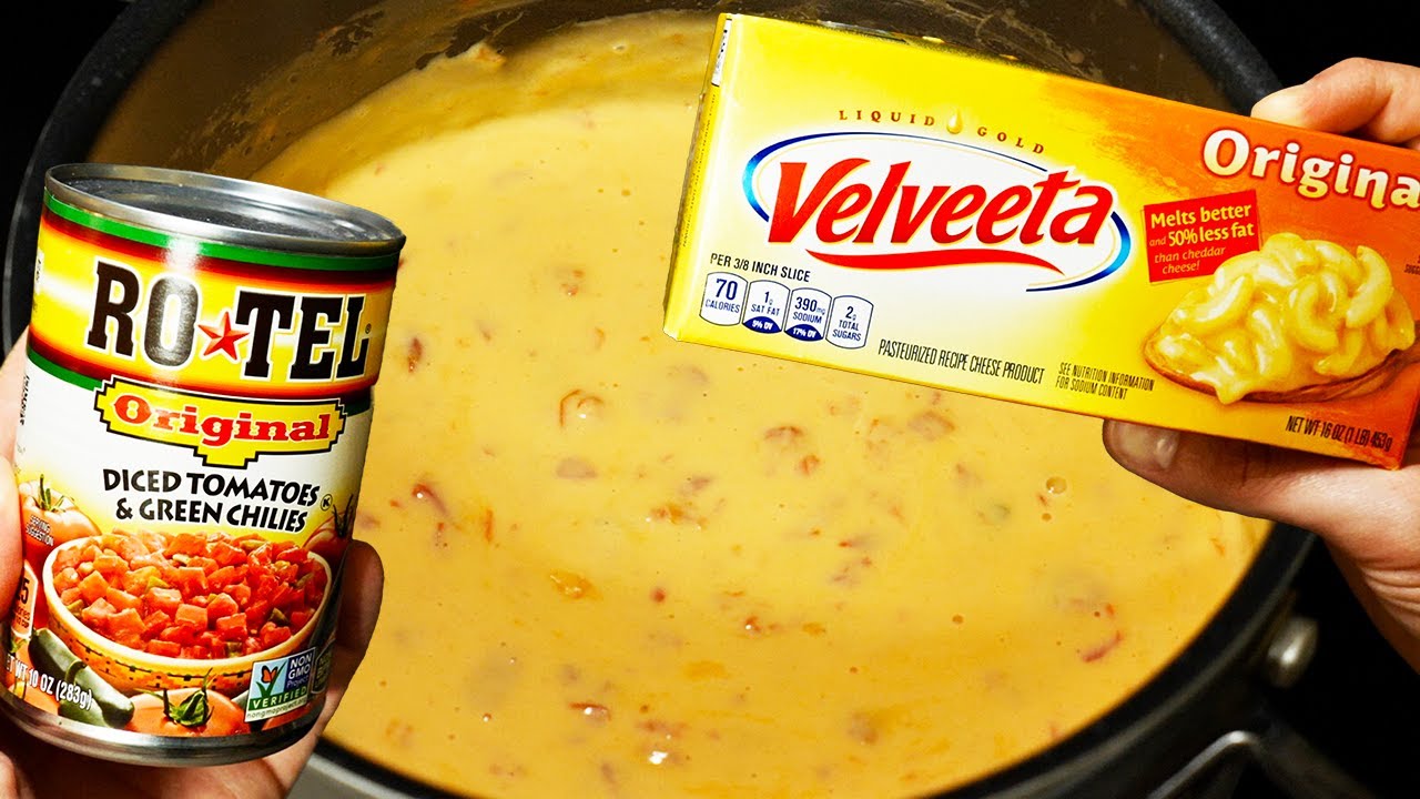 Cubed Velveeta and Rotel in a saucepan beginning to melt together with milk, stirred with a spatula on a stovetop