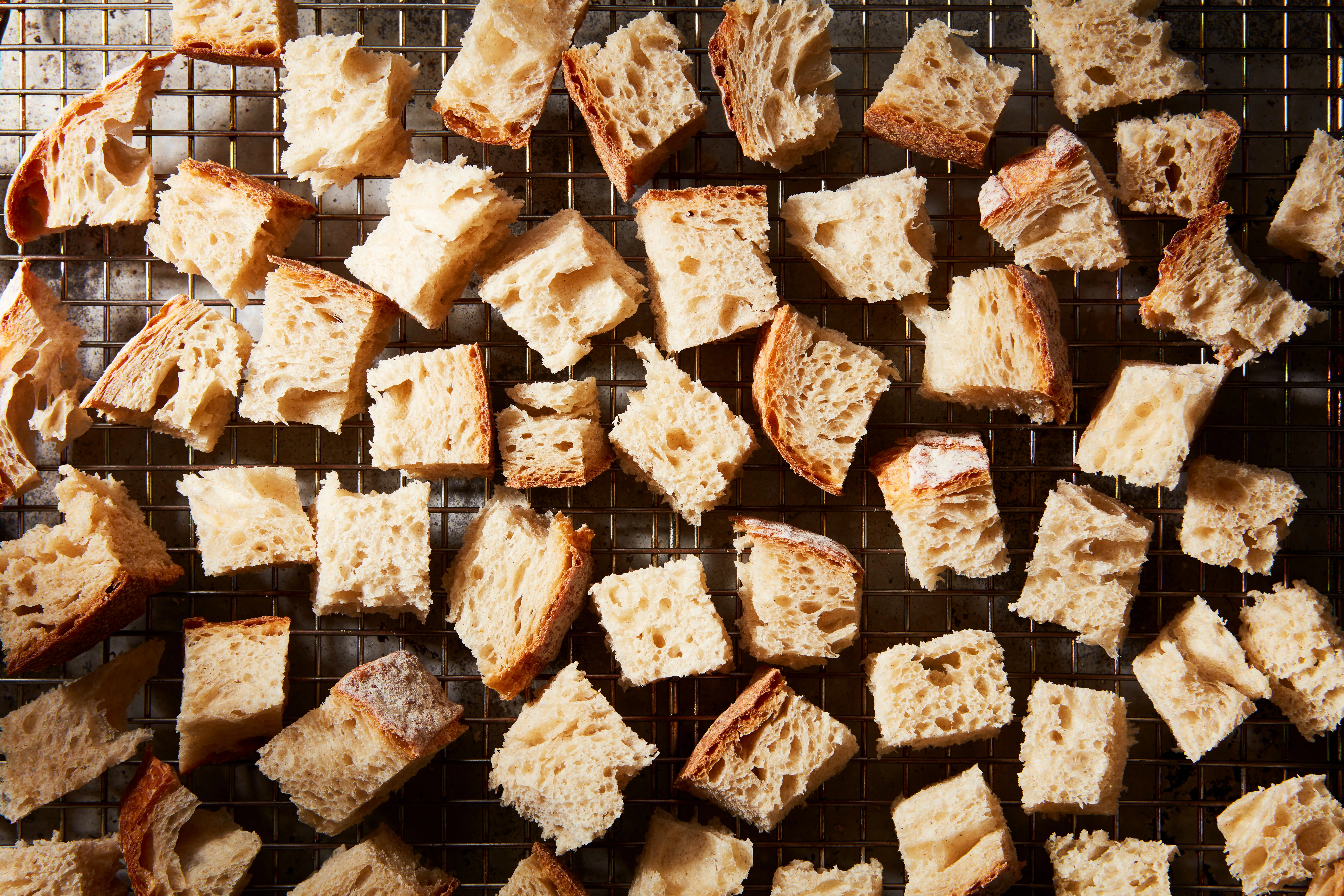 Cubed bread spread out on a rimmed baking sheet, ready to dry and toast for stuffing