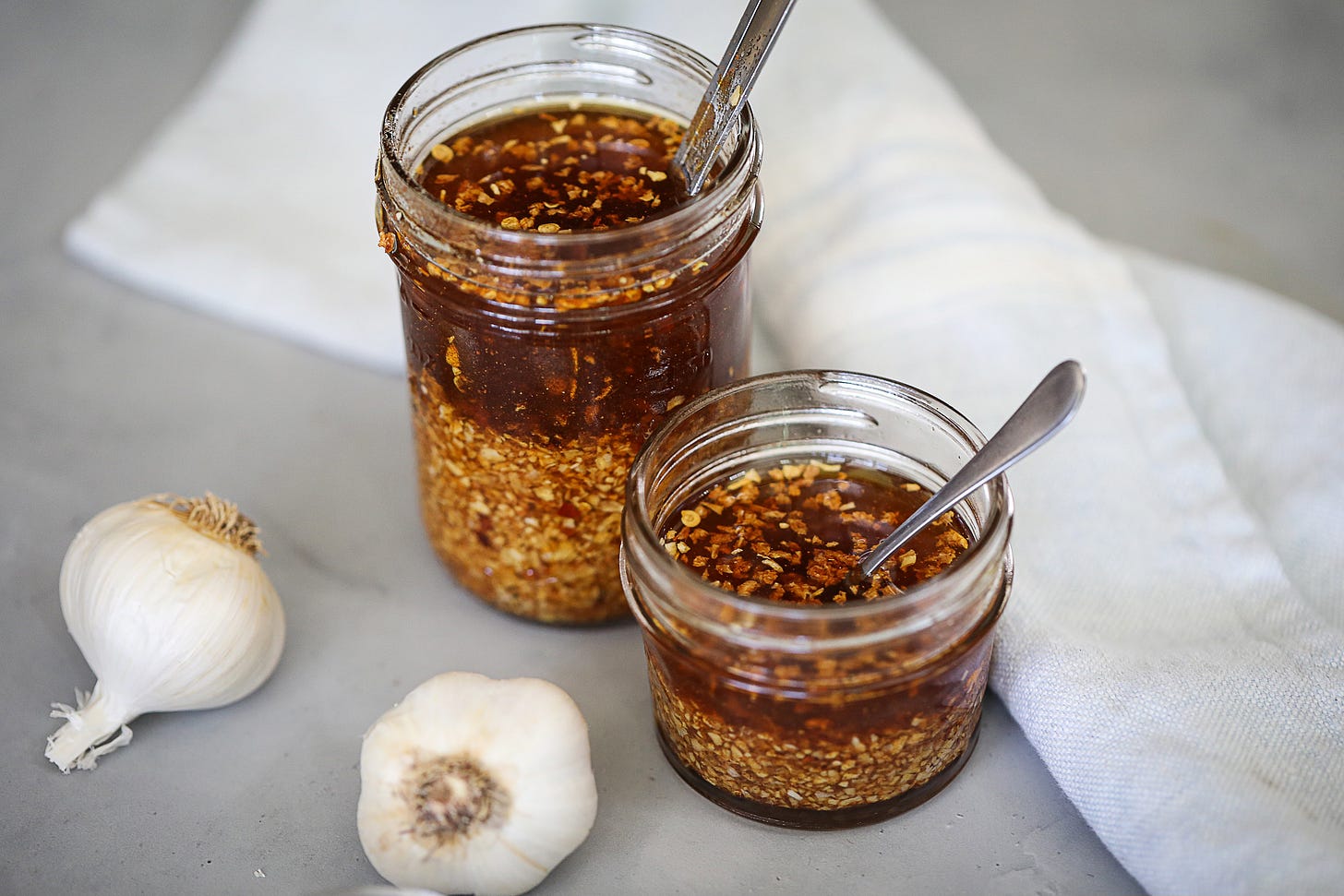 Diced onion and minced garlic on a cutting board next to small bowls of chili powder, cumin, paprika, and oregano on a kitchen counter