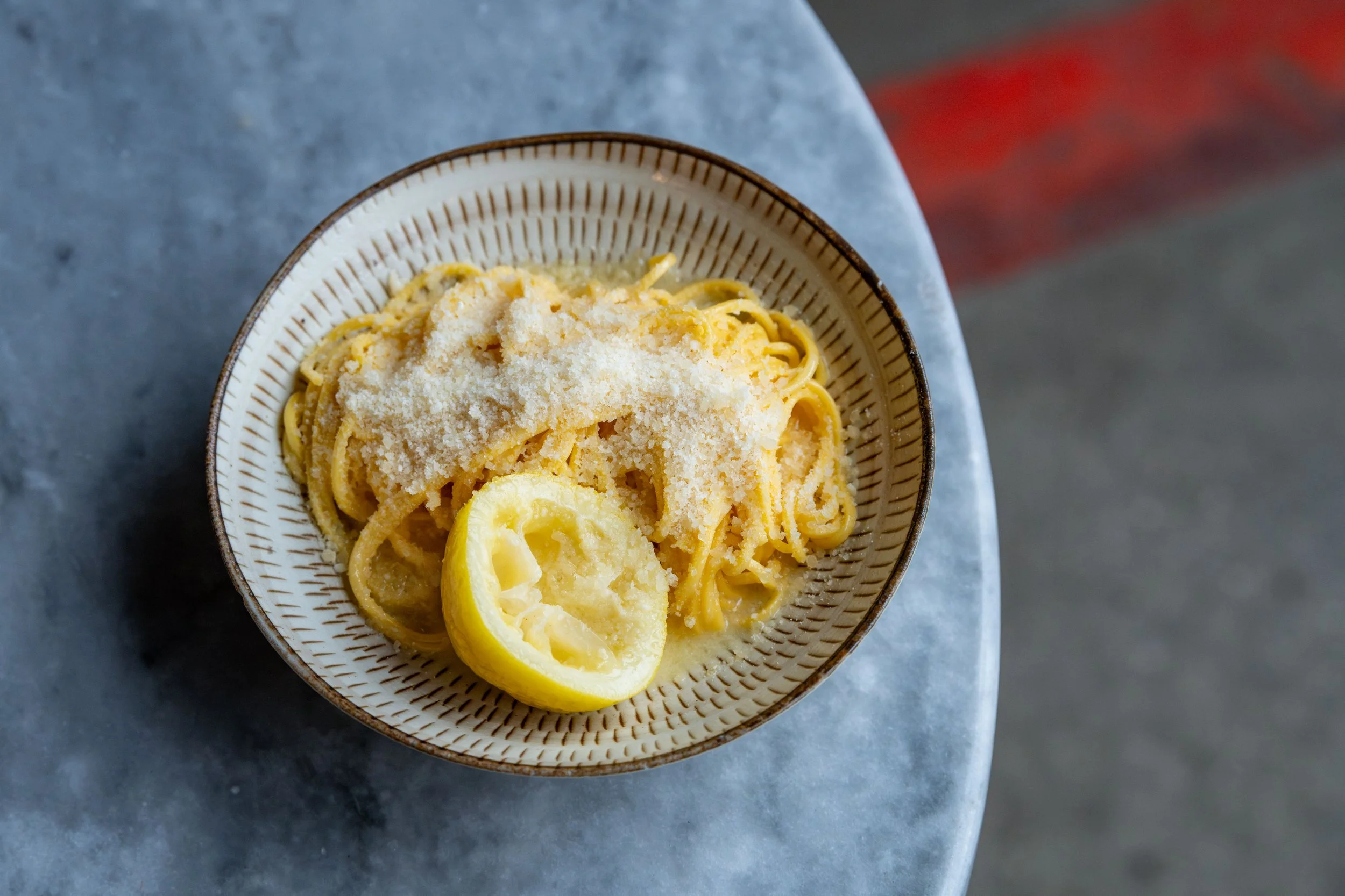 Egg yolks, finely grated Parmesan, butter, and a lemon arranged on a clean kitchen counter with a small bowl ready for mixing