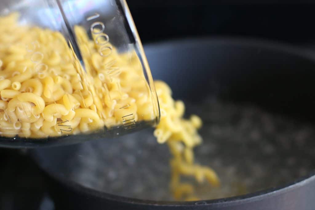 Elbow macaroni boiling in a large stainless steel pot on a stovetop