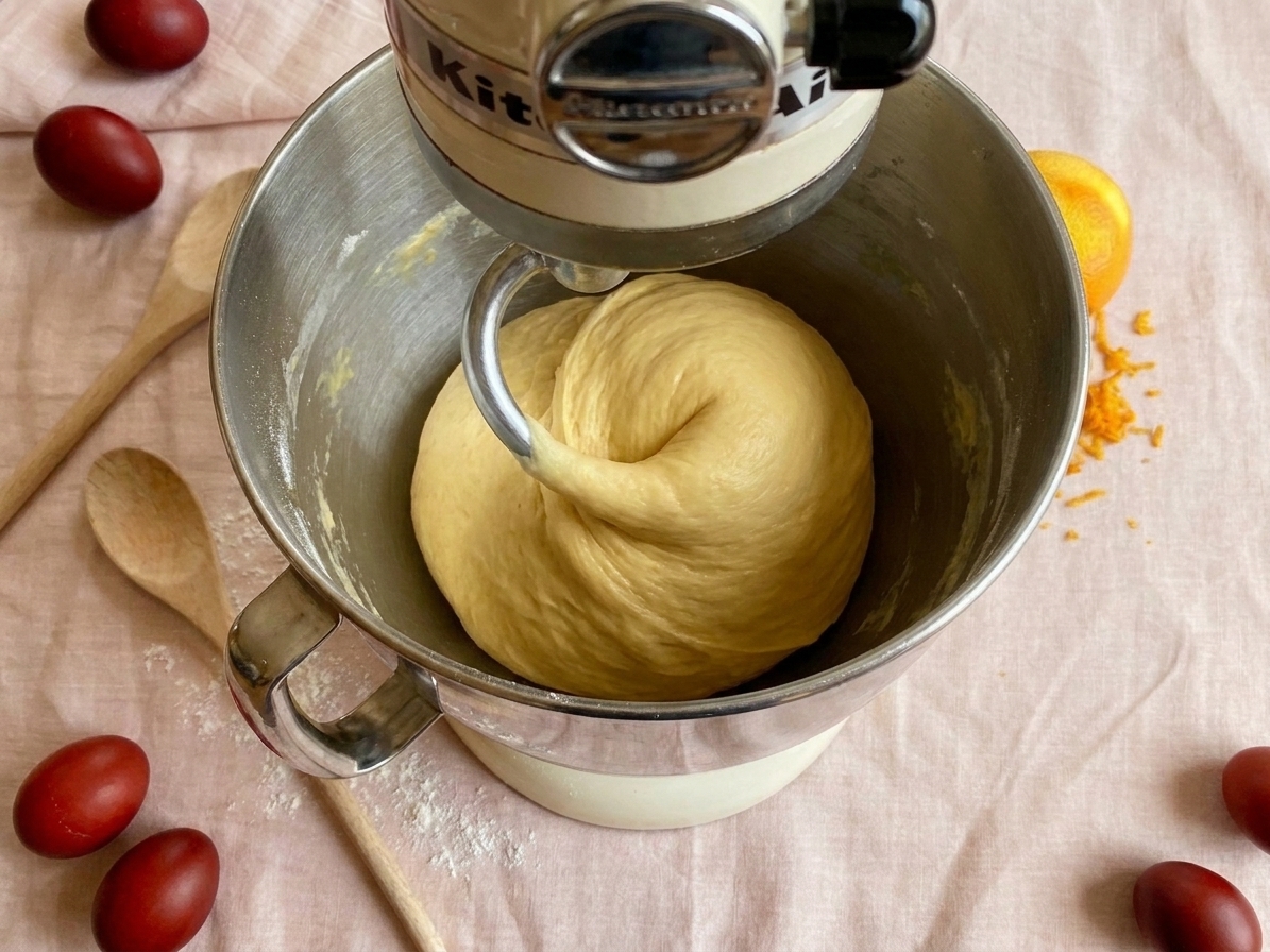 Enriched bread dough being kneaded in a stand mixer with a dough hook, smooth dough pulling from the sides of the bowl