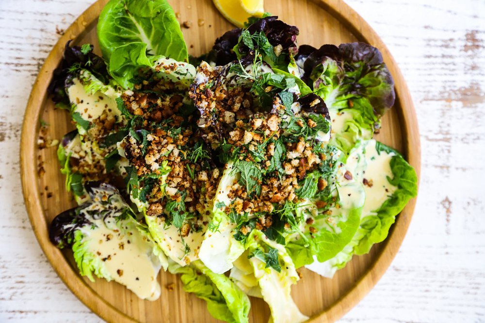 Finely grated Parmesan, a lemon half, and a peeled garlic clove on a cutting board, ready for Caesar dressing