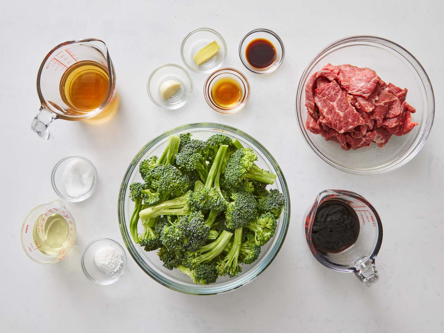 Flank steak, broccoli florets, soy sauce, brown sugar, garlic, ginger, cornstarch, and sesame oil arranged on a clean kitchen counter in natural light