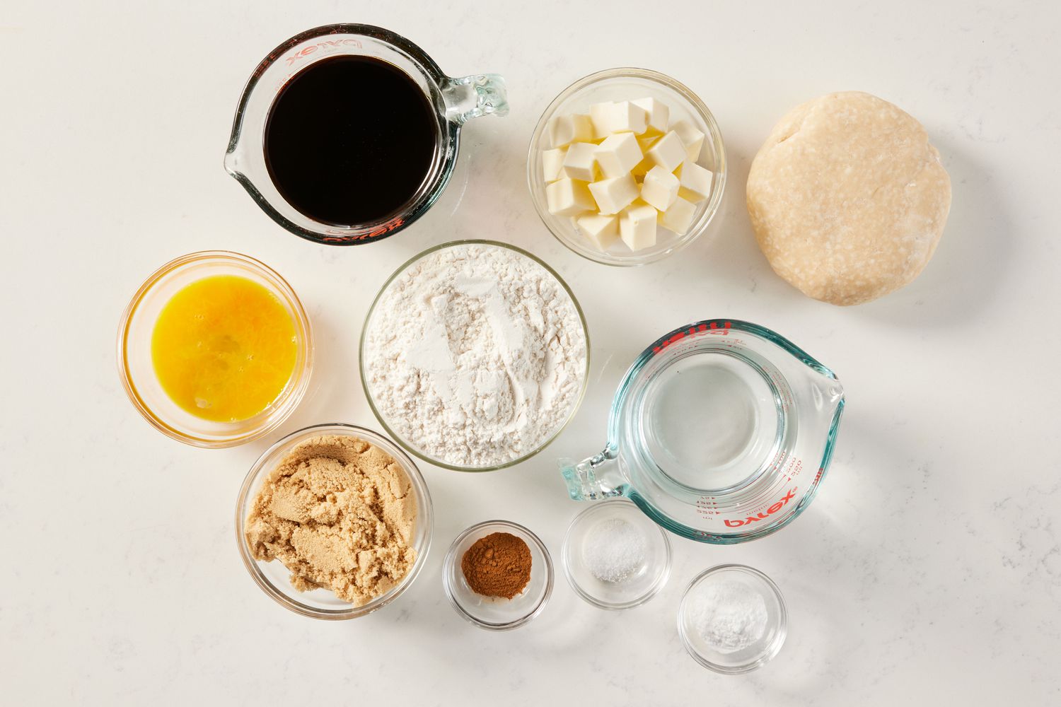 Flour, brown sugar, molasses, butter cubes, and spices measured out in small bowls on a tidy kitchen counter