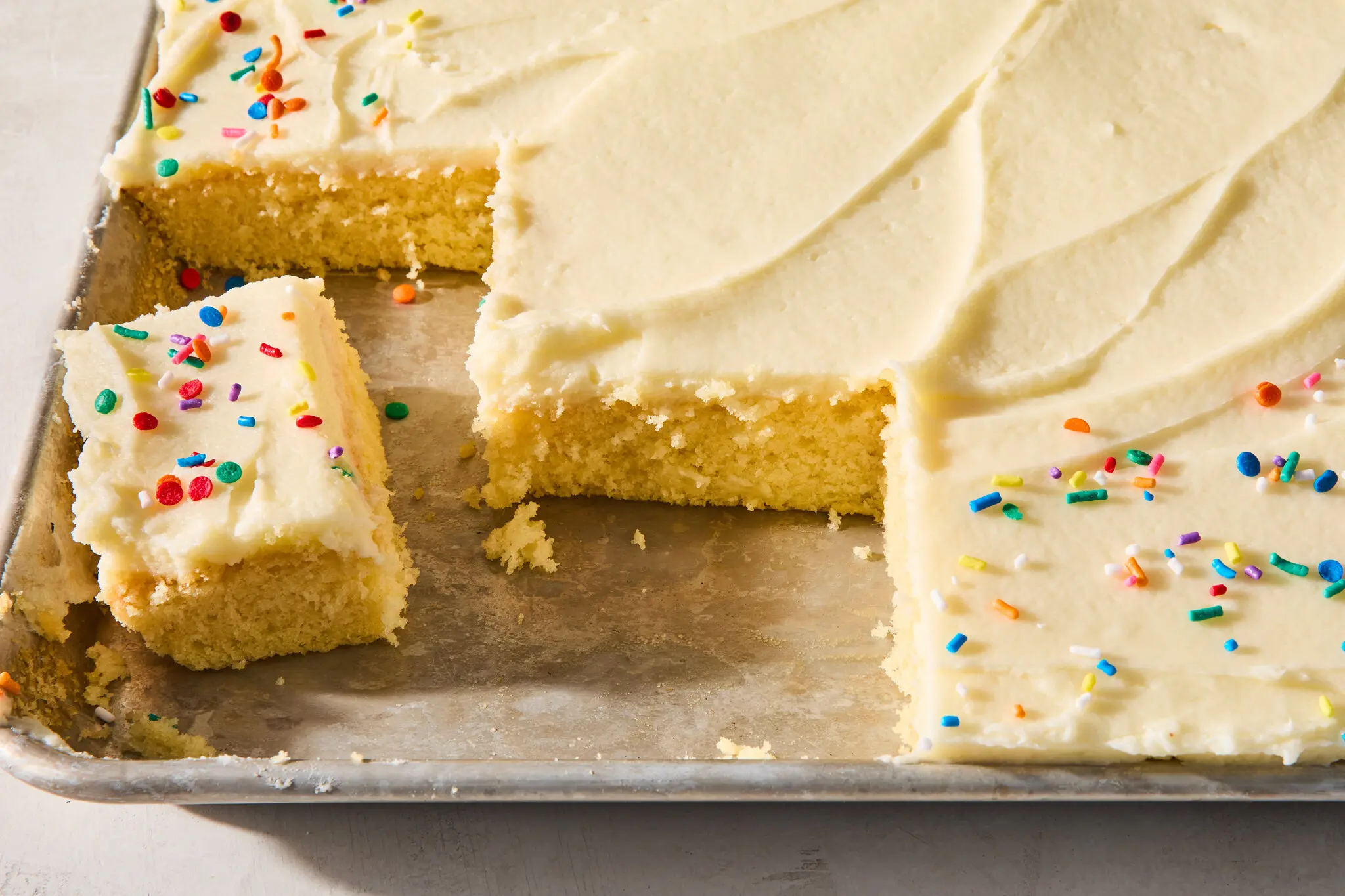 Flour, sugar, cocoa powder, butter, eggs, milk, sour cream, vanilla, and baking powder arranged on a clean kitchen counter with measuring cups