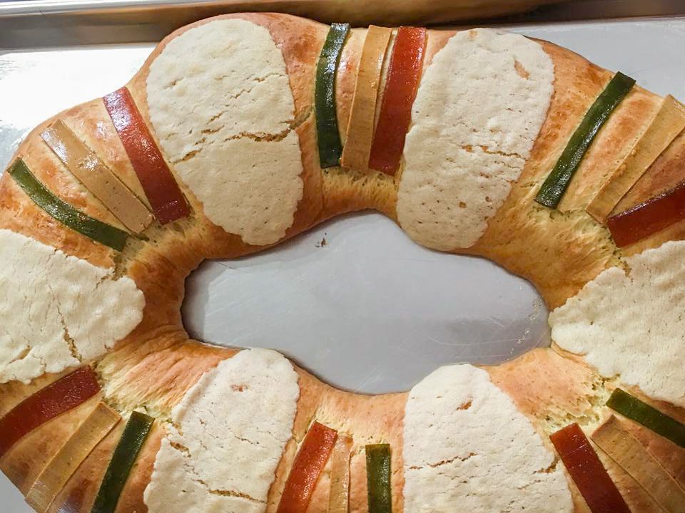 Flour, sugar, eggs, milk, butter, oranges, yeast, and candied fruit arranged on a bright kitchen counter in small bowls