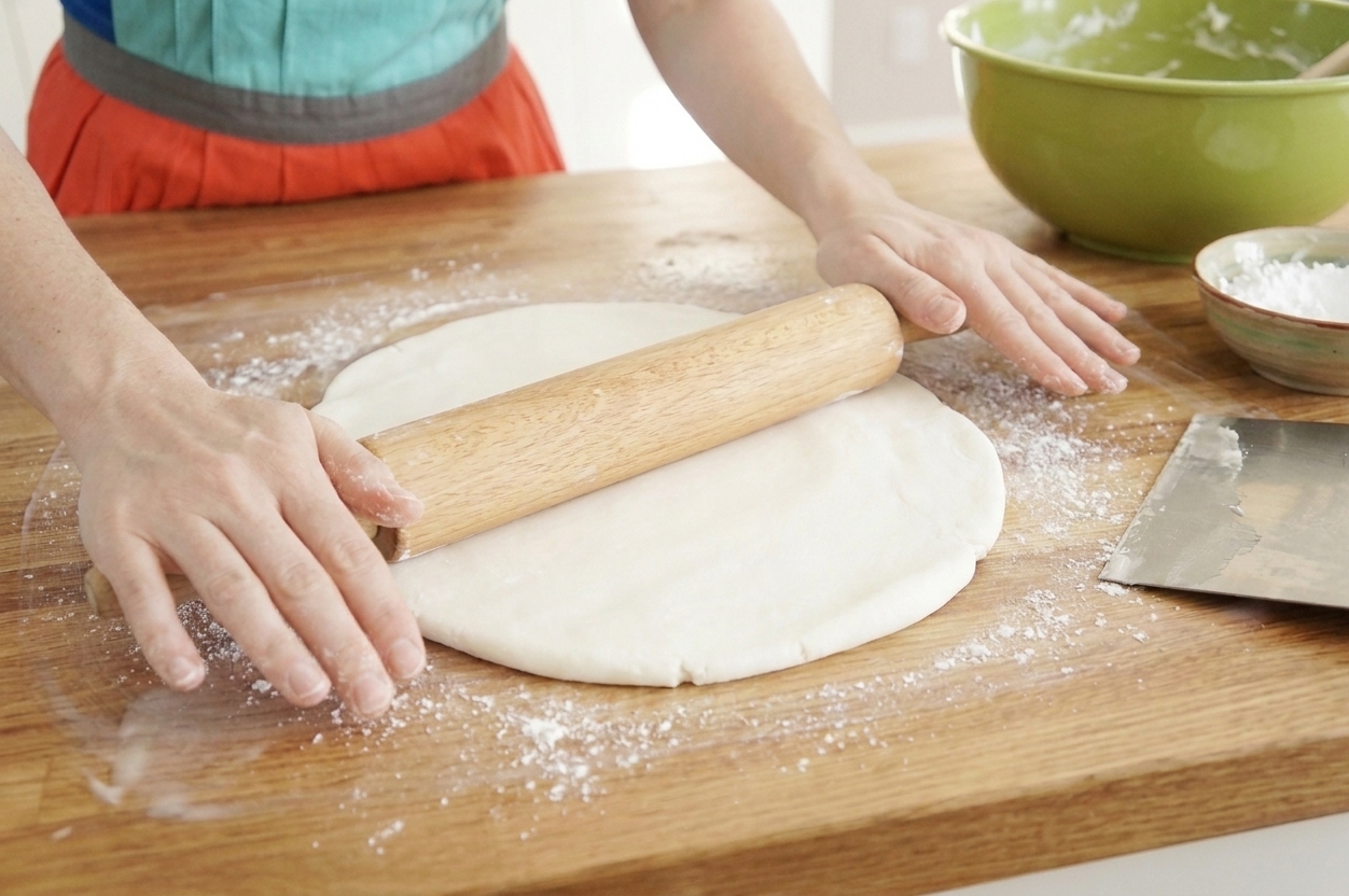 Fondant being rolled out with a rolling pin on a clean counter