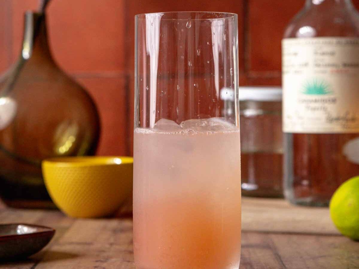 Fresh grapefruit, limes, tequila, sparkling water, and a small dish of salt and chili powder arranged on a tidy kitchen counter