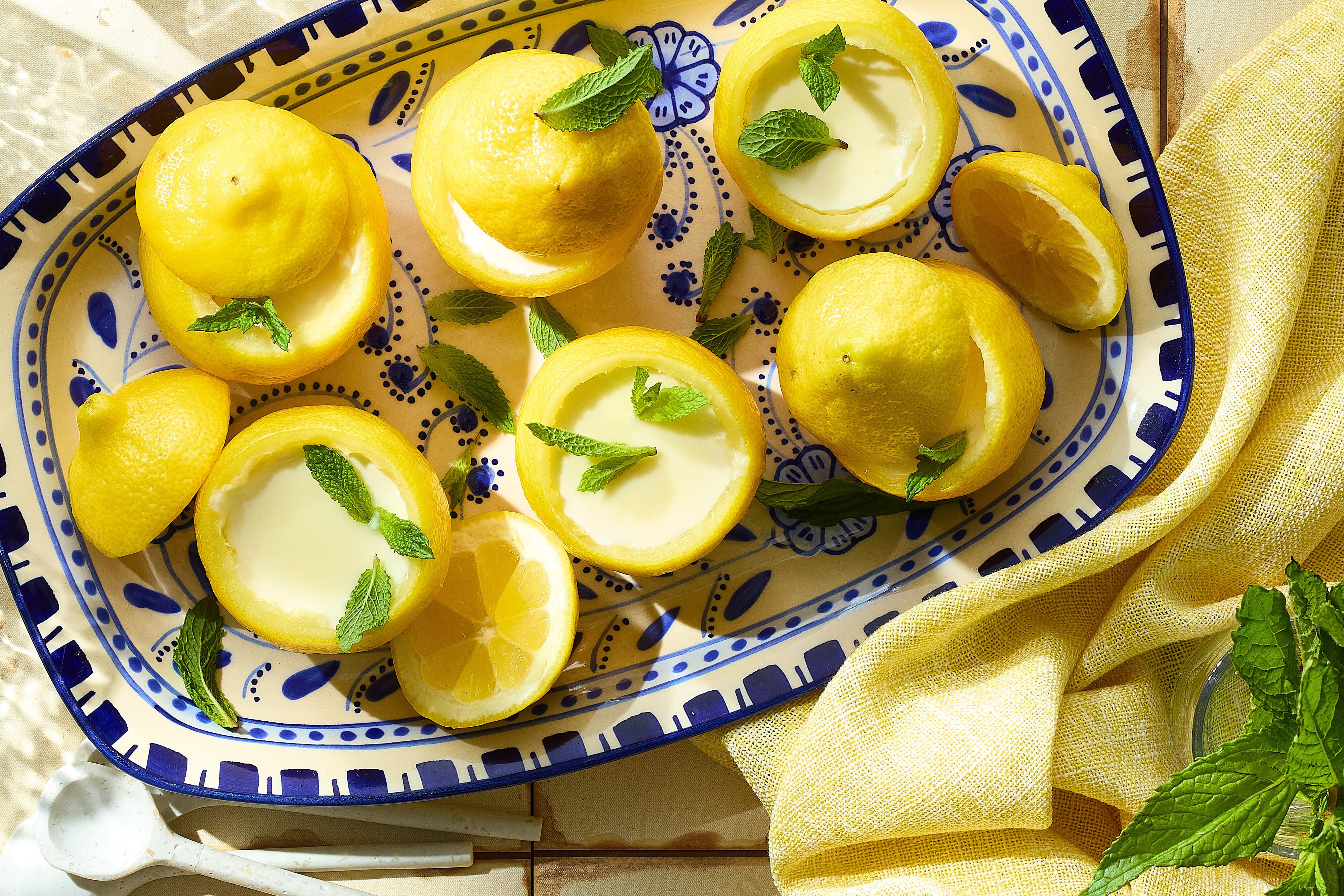 Fresh lemons, heavy cream, sugar, and vanilla arranged on a clean kitchen counter with measuring cups and a microplane nearby