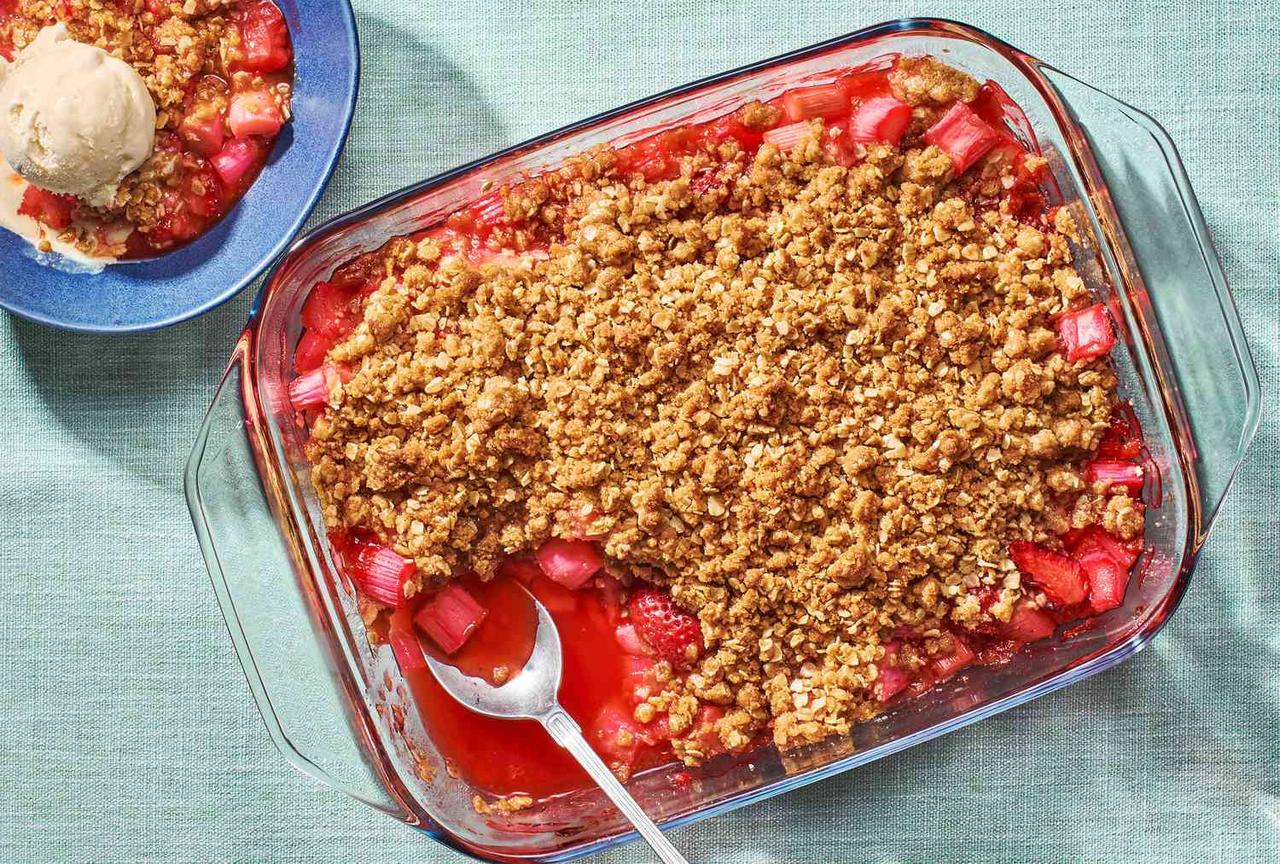 Fresh strawberries, chopped rhubarb, rolled oats, flour, brown sugar, and butter arranged on a bright kitchen counter ready for baking