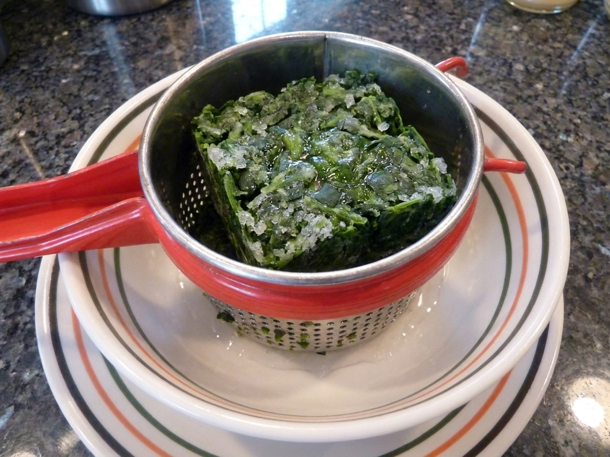Frozen chopped spinach thawing in a bowl on a kitchen counter, ready to be squeezed dry before making dip