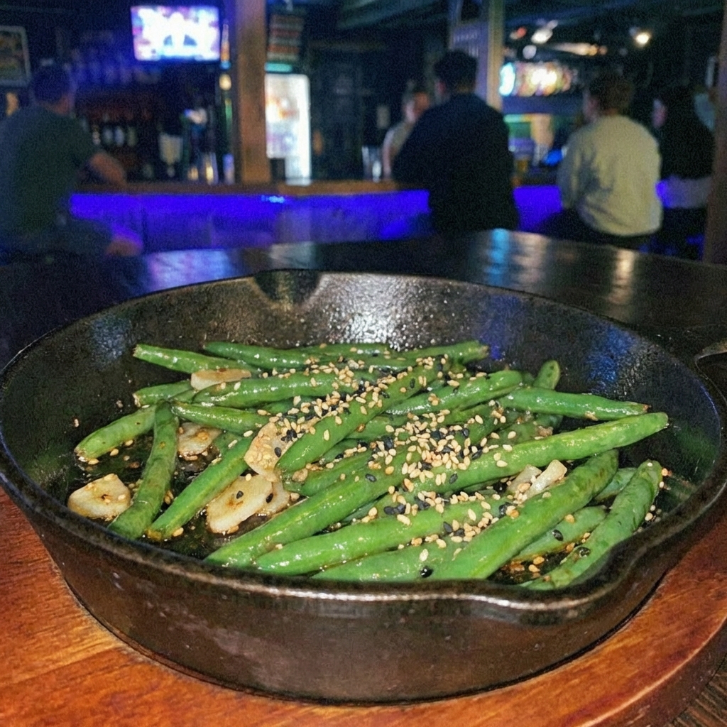 Garlic sautéed green beans in a skillet with toasted sesame seeds