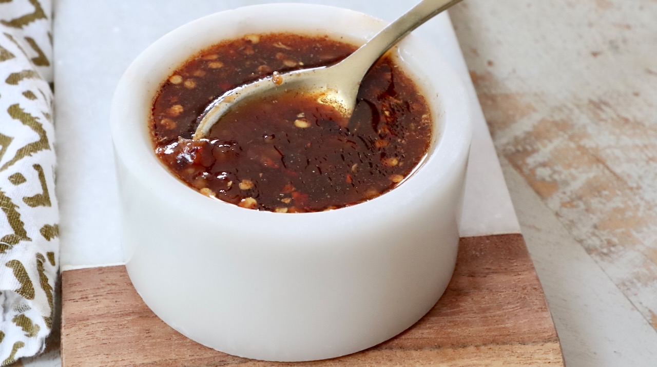 General Tso sauce gently simmering in a small saucepan with a whisk resting inside as the surface turns glossy