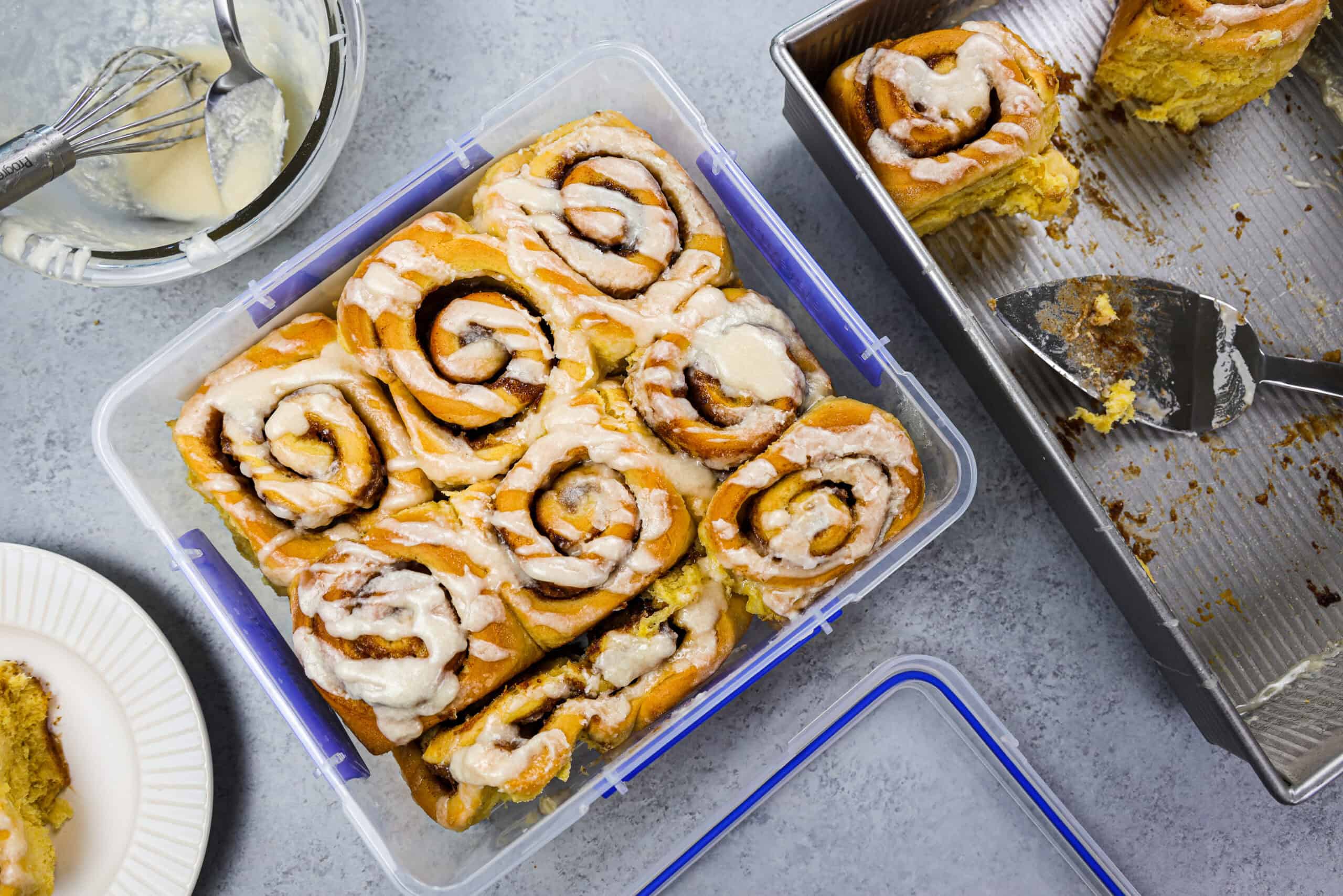 Gluten free cinnamon rolls stored in an airtight container on a kitchen counter with a lid set beside it