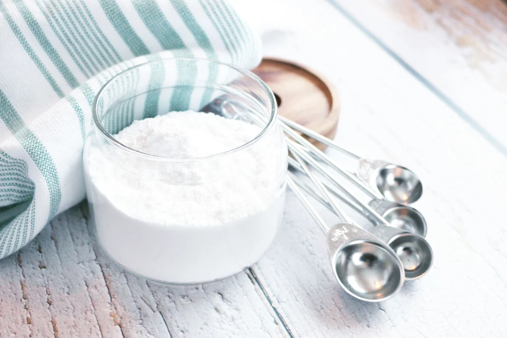 Gluten-free flour blend and baking powder measured in small bowls on a kitchen counter
