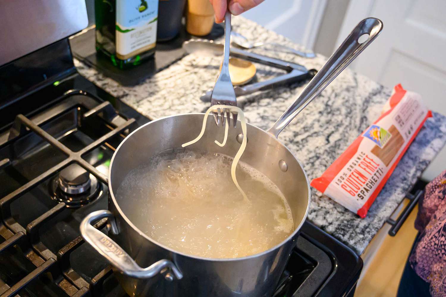 Gluten free spaghetti boiling in a large stainless steel pot on a home stove with gentle steam rising