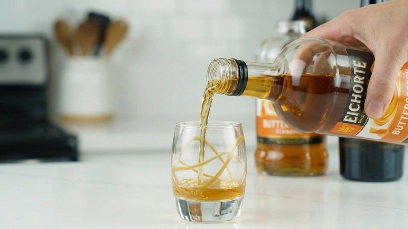 Golden butterscotch schnapps poured into a clear shot glass